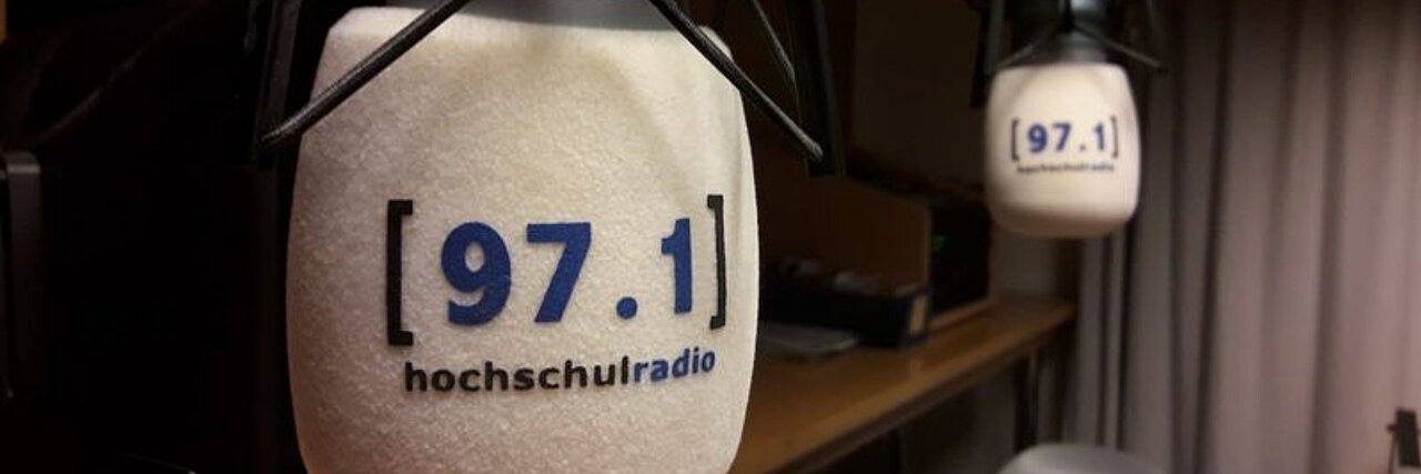 In einem Radiostudio hängen zwei Mikrofone gegenüber. Auf beiden steht 97.1 hochschulradio